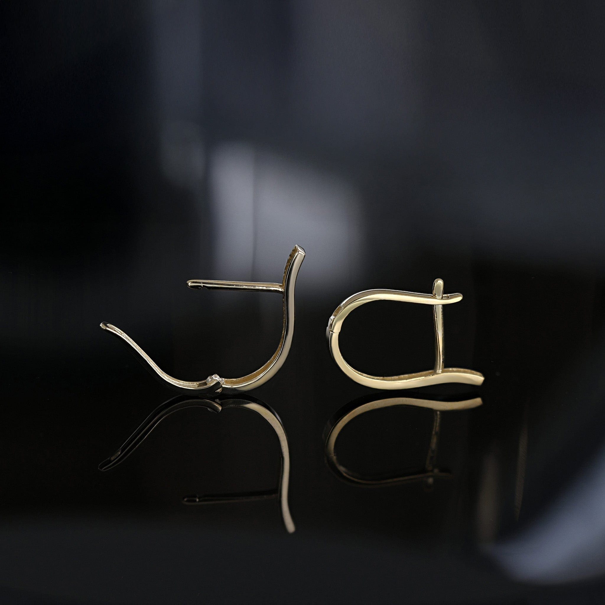 Gold earrings on a reflective surface with a dark background