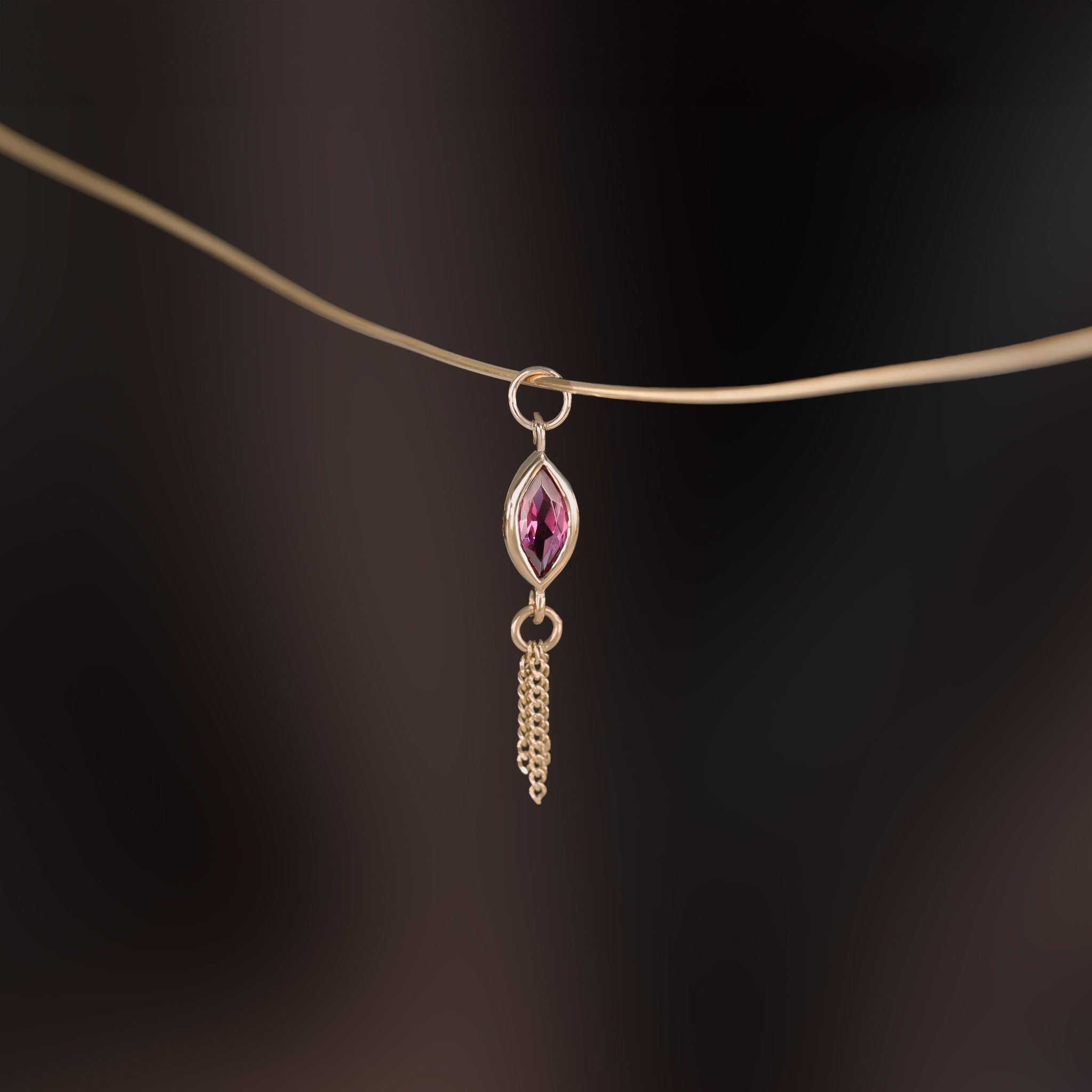 14K gold charm of a a marquise-cut Rhodolite Garnet paired with three delicate gold curb chain tassels