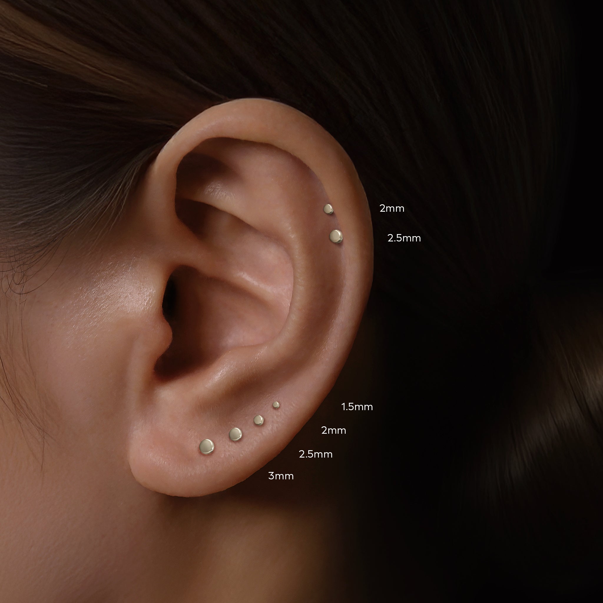 Four sizes of Titanium flat disc studs worn on an actual ear on both Lobe and helix piercing.