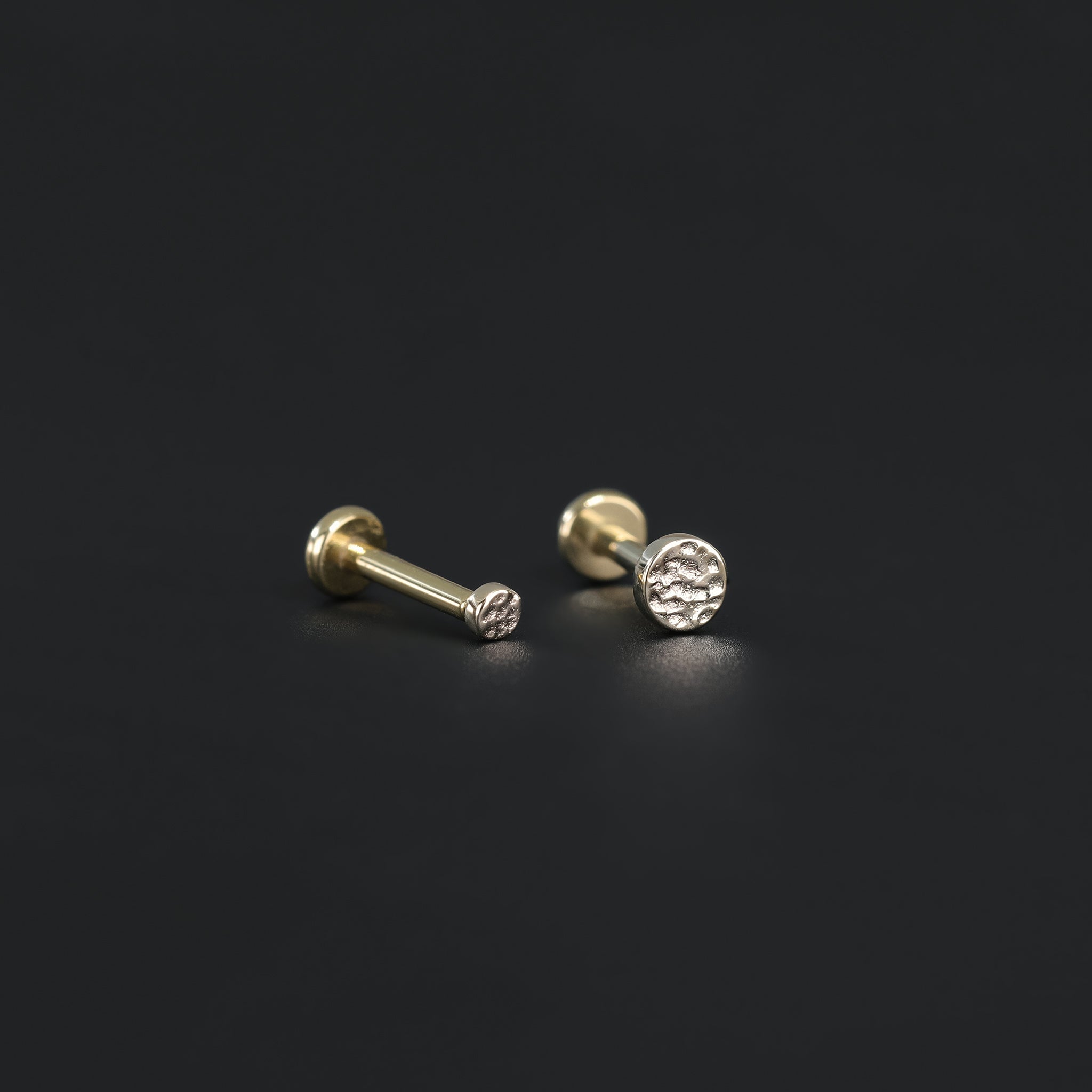 2mm and 3mm 14K Gold Hammered disc studs in yellow gold displayed on black surface.