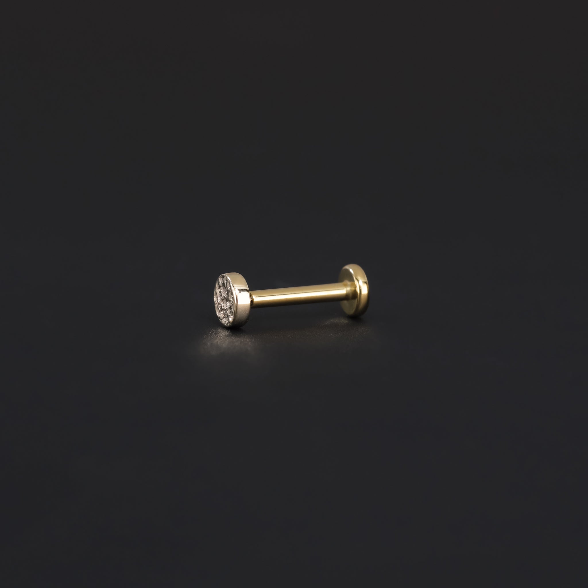 Side view of 3mm 14K Gold Hammered disc studs in yellow gold displayed on black surface.