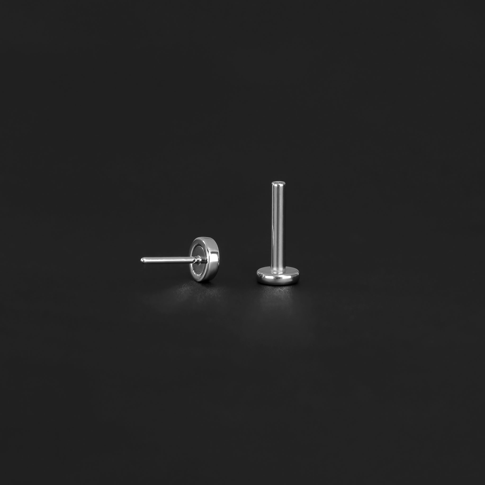 Push pin of 14K Gold Hammered disc studs in white gold back view and Titanium post displayed on black surface.