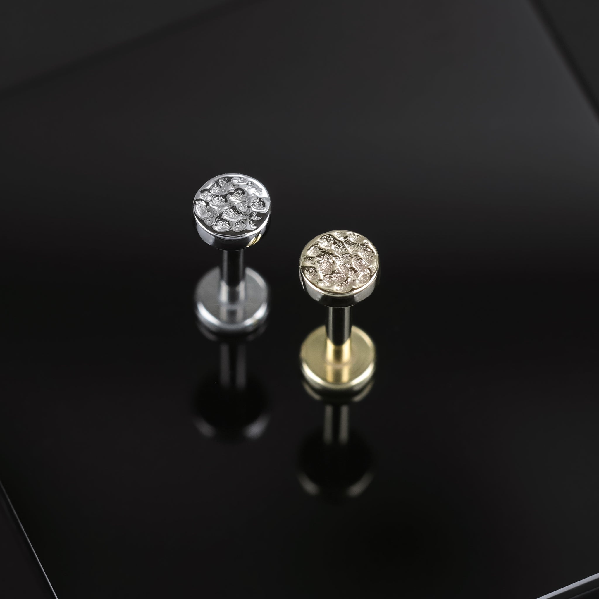 3mm 14K Gold Hammered disc studs in yellow gold and white gold displayed on black surface, featuring its textured surface on a disc.