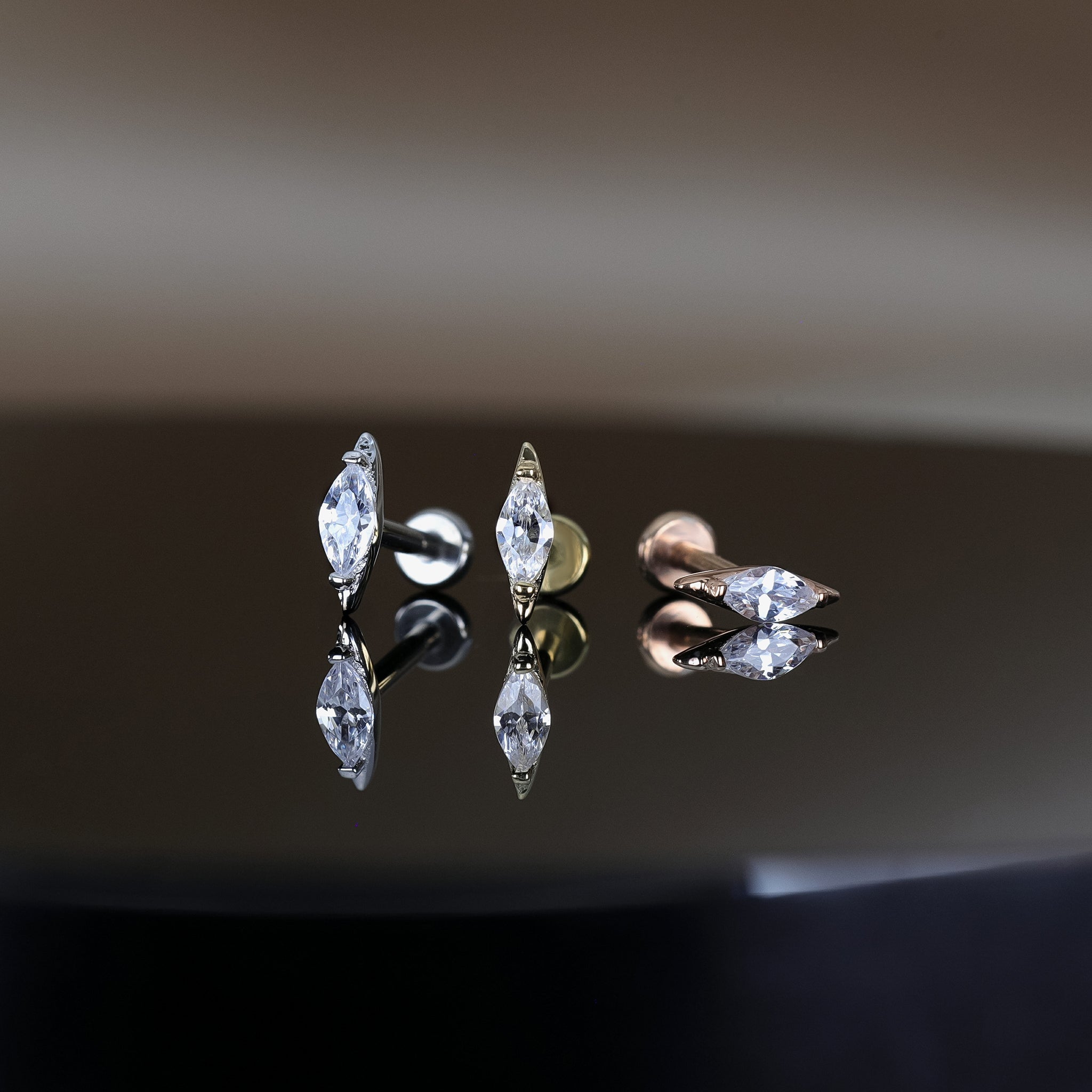 14K Gold Marquise Cubic Zirconia studs in yellow gold, white gold and rose gold displayed on black surface, featuring its sparkles of the stone