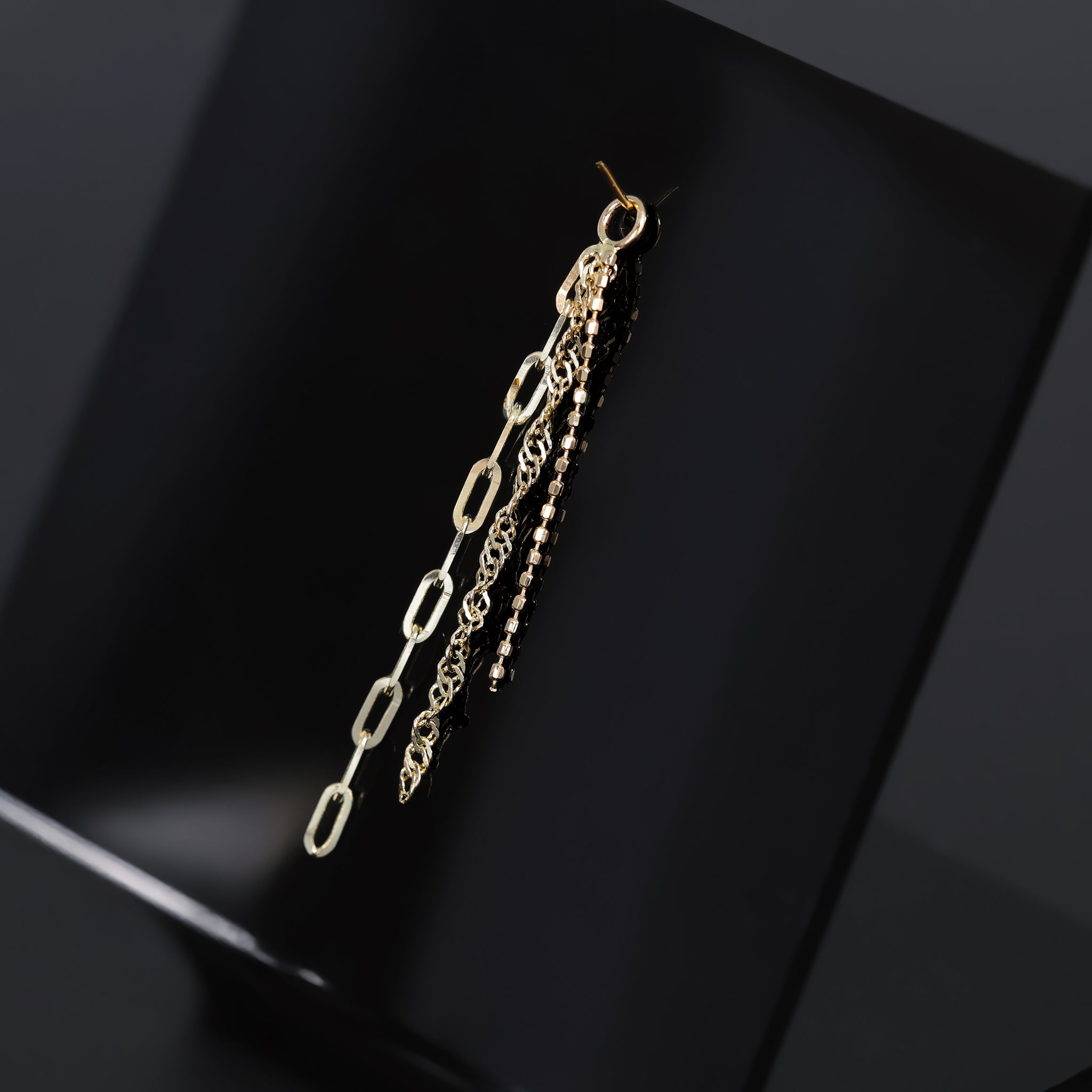 14K yellow gold mixed chain charm that comes with clip chain, box chain and Singapore chain displayed on black surface